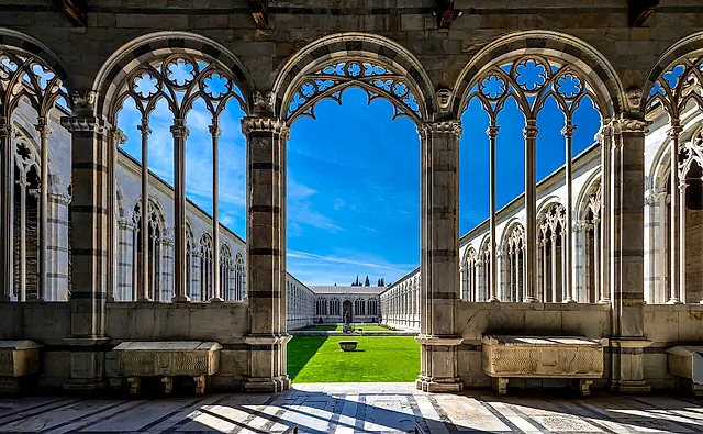 Gli archi gotici del Camposanto Monumentale che incorniciano il cortile verde al sole