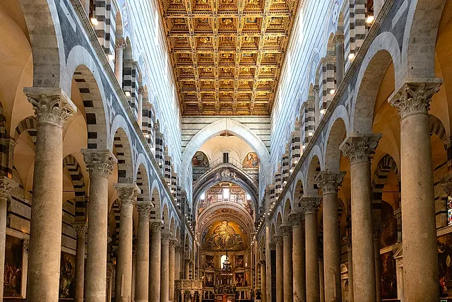 L'interno della Cattedrale di Pisa: la navata con le alte colonne, il soffitto a cassettoni dorato e l'abside in fondo