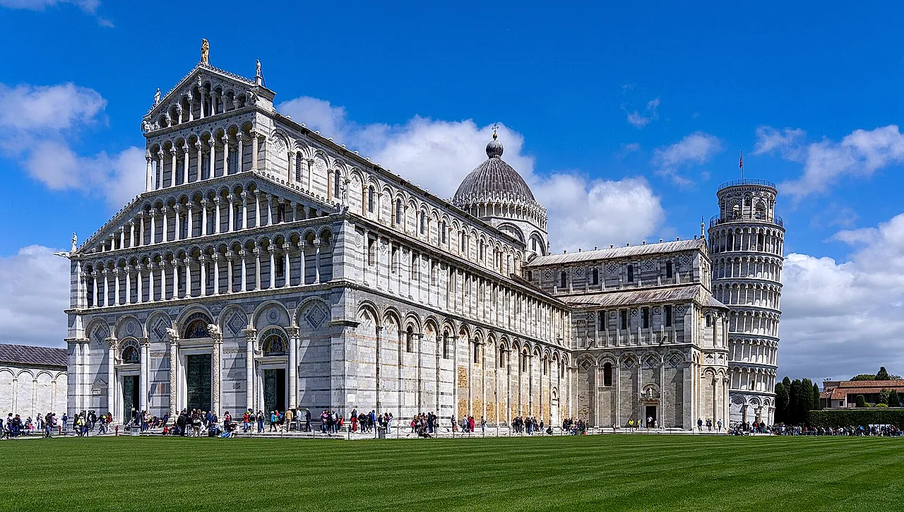 La facciata della Cattedrale di Pisa con i suoi piani di arcate in marmo bianco e grigio e la Torre pendente a destra, sul prato di Piazza dei Miracoli