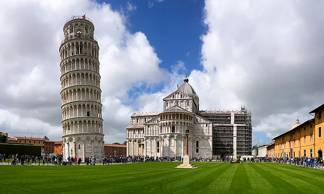 La Torre pendente e la Cattedrale una accanto all'altra sul prato verde di Piazza dei Miracoli sotto un cielo nuvoloso