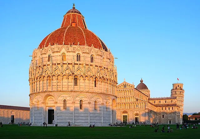 La cupola rivestita di tegole rosse del Battistero nella luce calda della sera, con la Cattedrale e la Torre pendente dietro