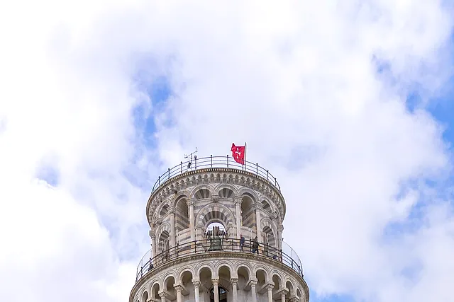 La Torre pendente di Pisa vista dal basso, con i piani di arcate inclinati su un lato sotto un cielo nuvoloso