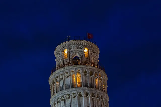 La Torre pendente di Pisa illuminata di notte contro un cielo blu intenso